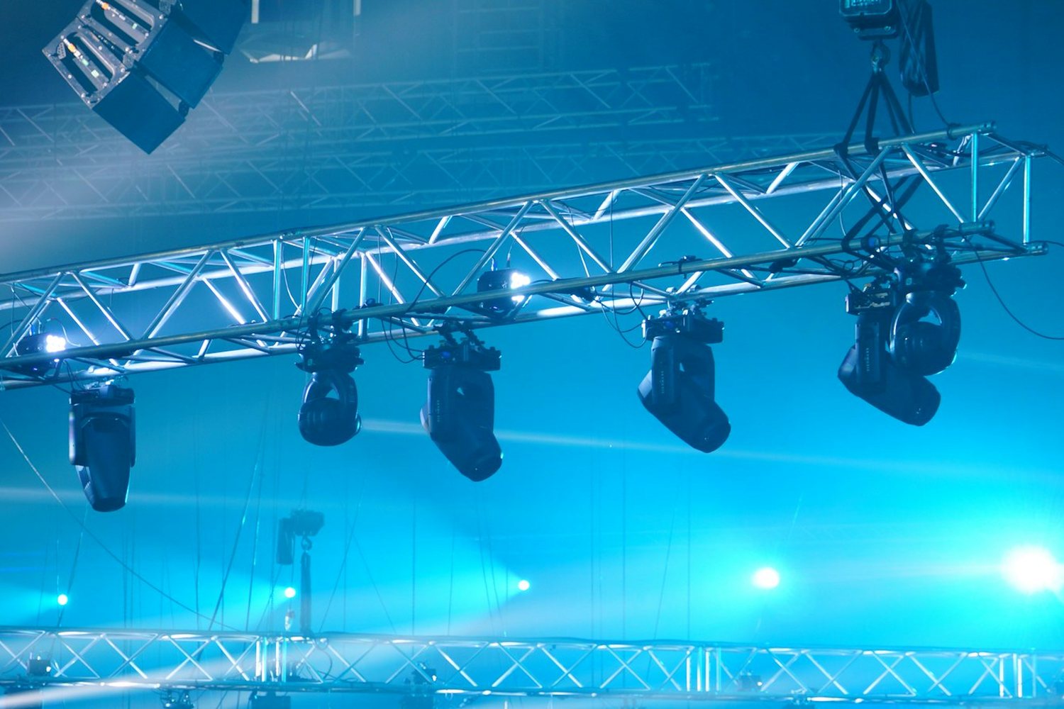 Lighting fixtures rigged on a blue-lit truss