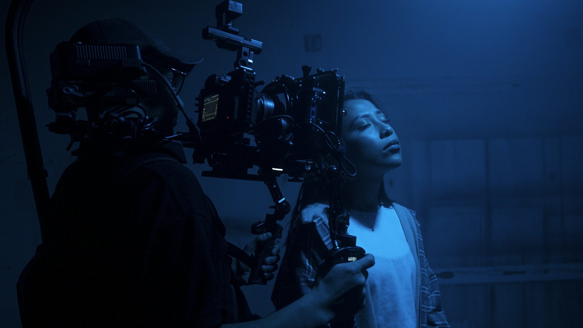 Camera operator filming in blue stage light