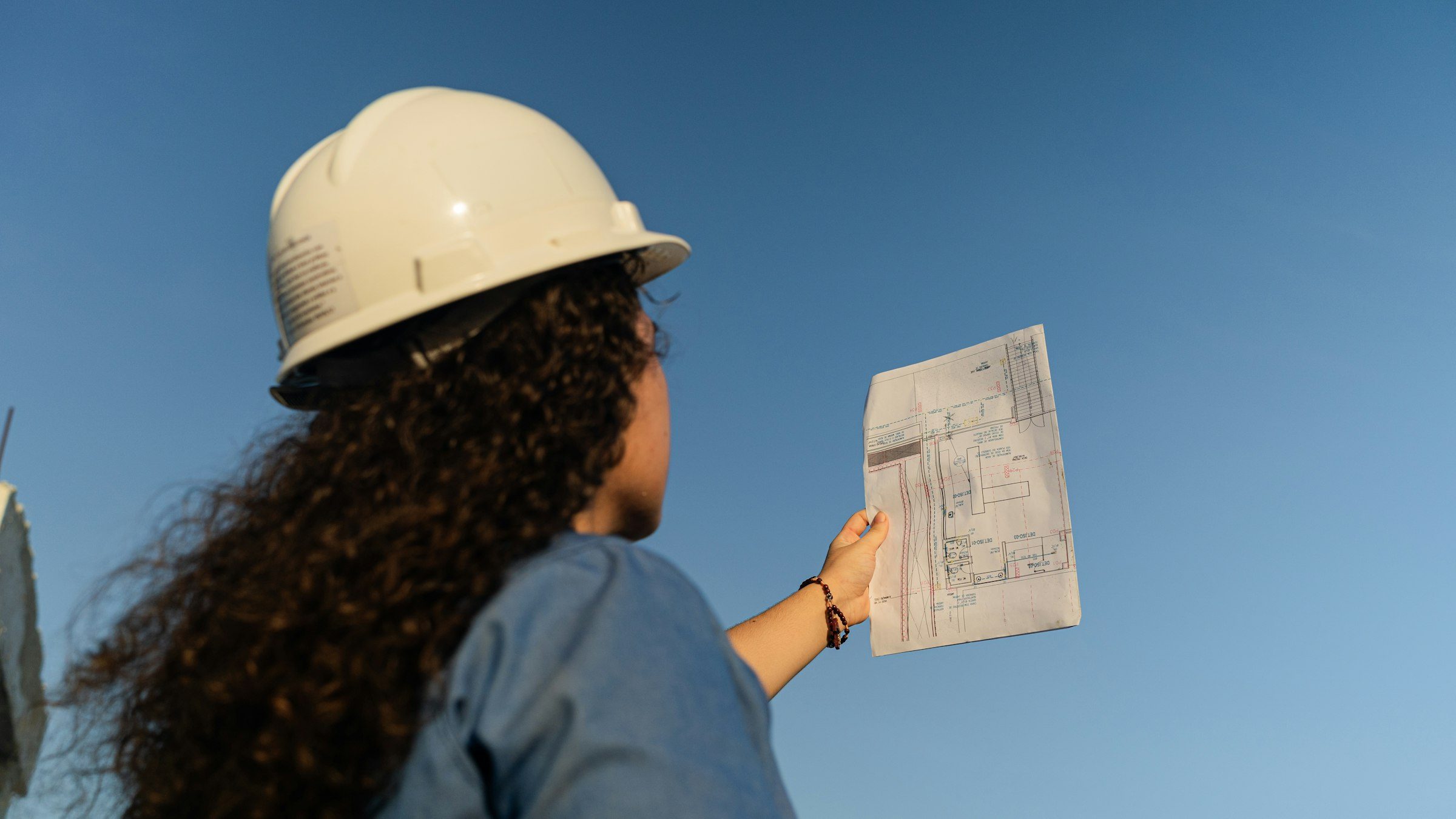 Engineer in a hard hat reviewing drawings on site