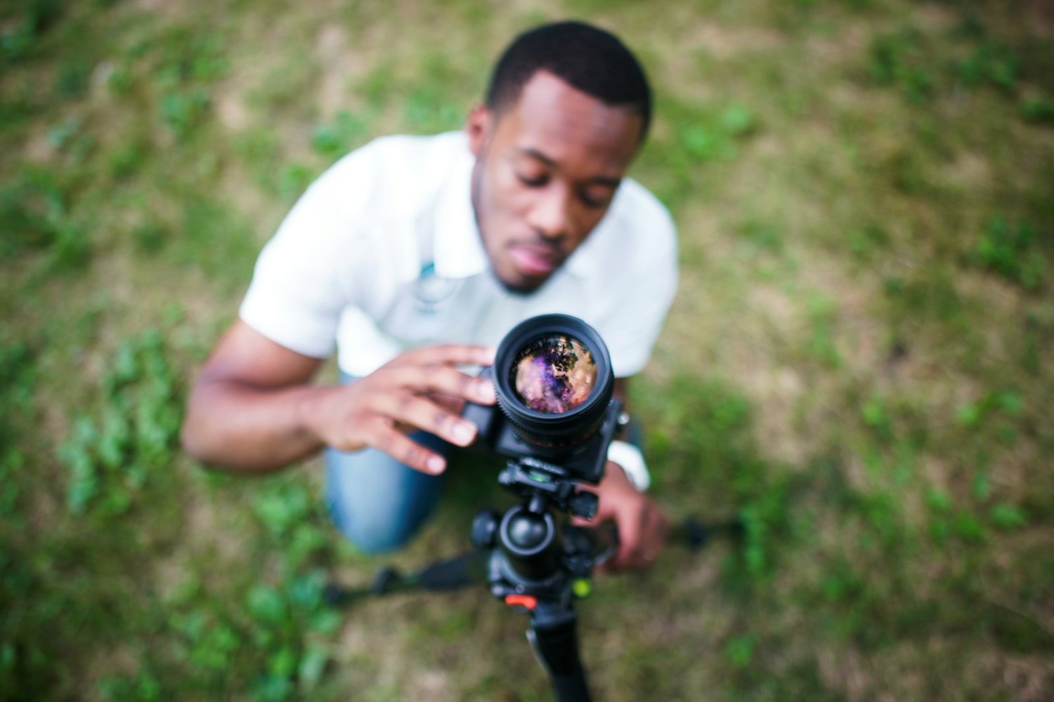 Photographer crouching low on grass with a camera